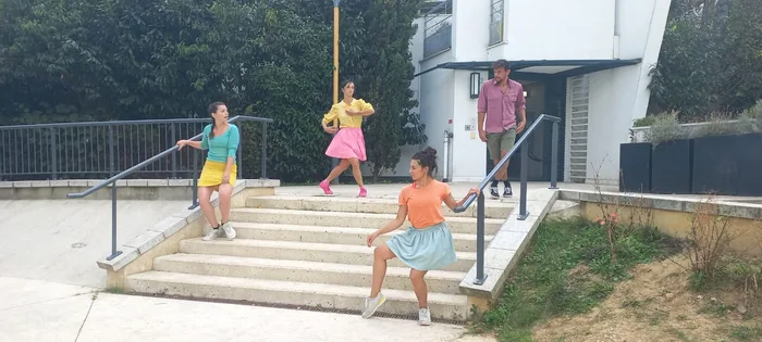 Un groupe de danseurs menant le public dans une rue, en plein jour