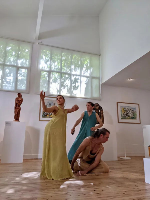 Gros plan sur le geste d’une danseuse devant une œuvre encadrée