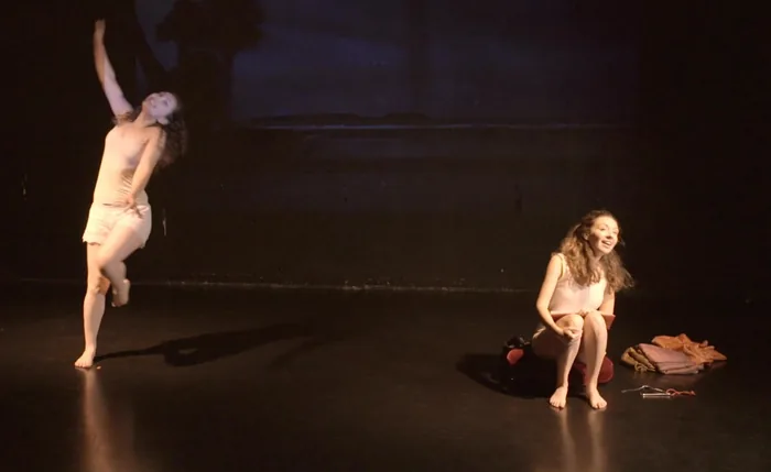 La danseuse lance un bras vers le ciel, la conteuse assise sur un coussin rit